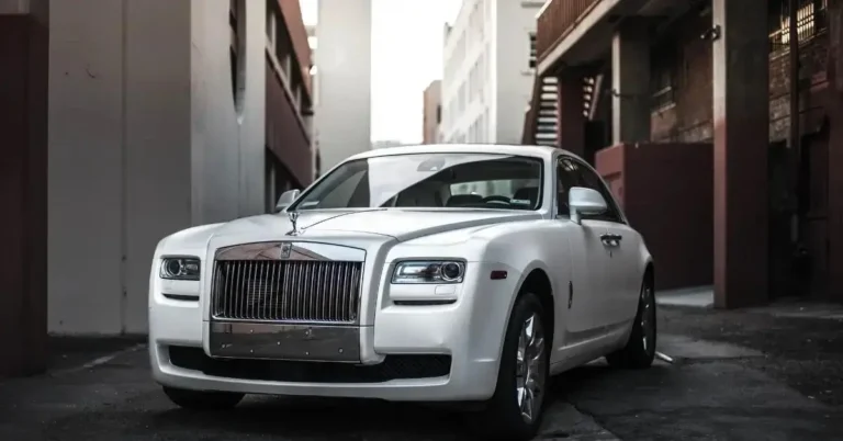 A white Rolls Royce Phantom standing in a Lane between buildings
