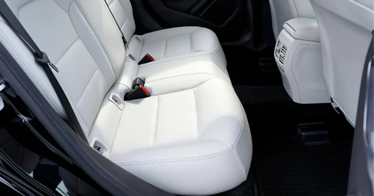 The look into the back seats of a car with door open, white seats and black carpet