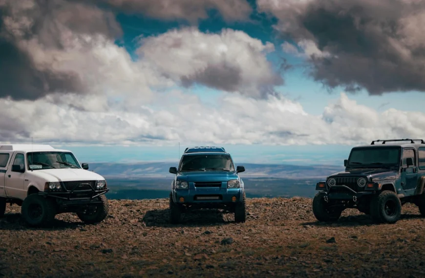 Three Offroad cars standing on a sandy terrain with the Heaven in the back