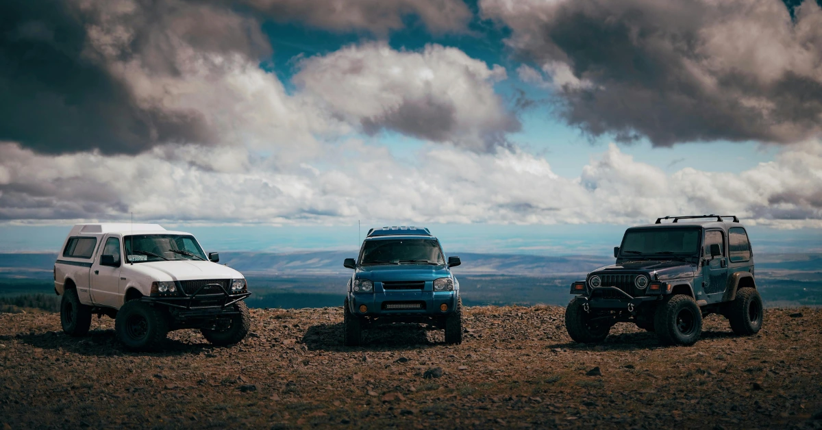 Three Offroad cars standing on a sandy terrain with the Heaven in the back