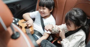 Two children sitting on the backseat of a car.