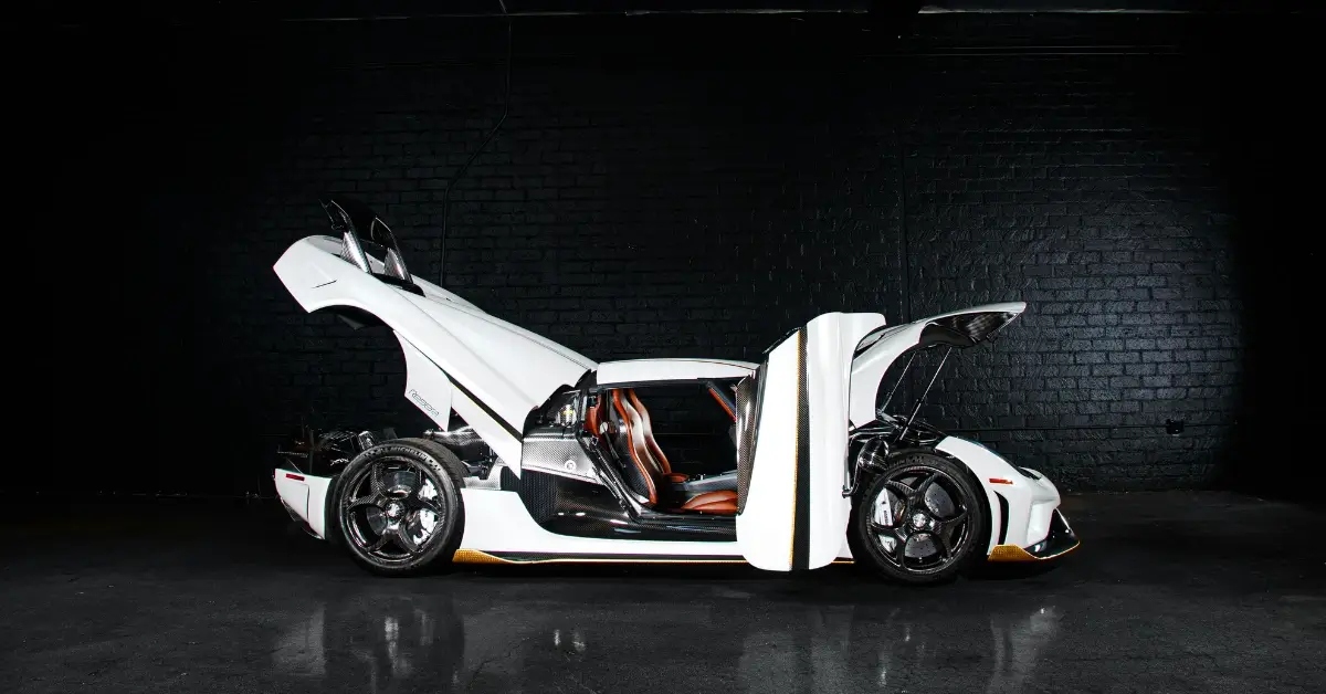 A white Koenigsegg Regera standing in a black box with all toors open