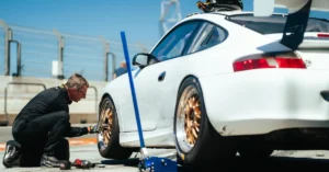 A Driver changing the front left wheel of his white Porsche