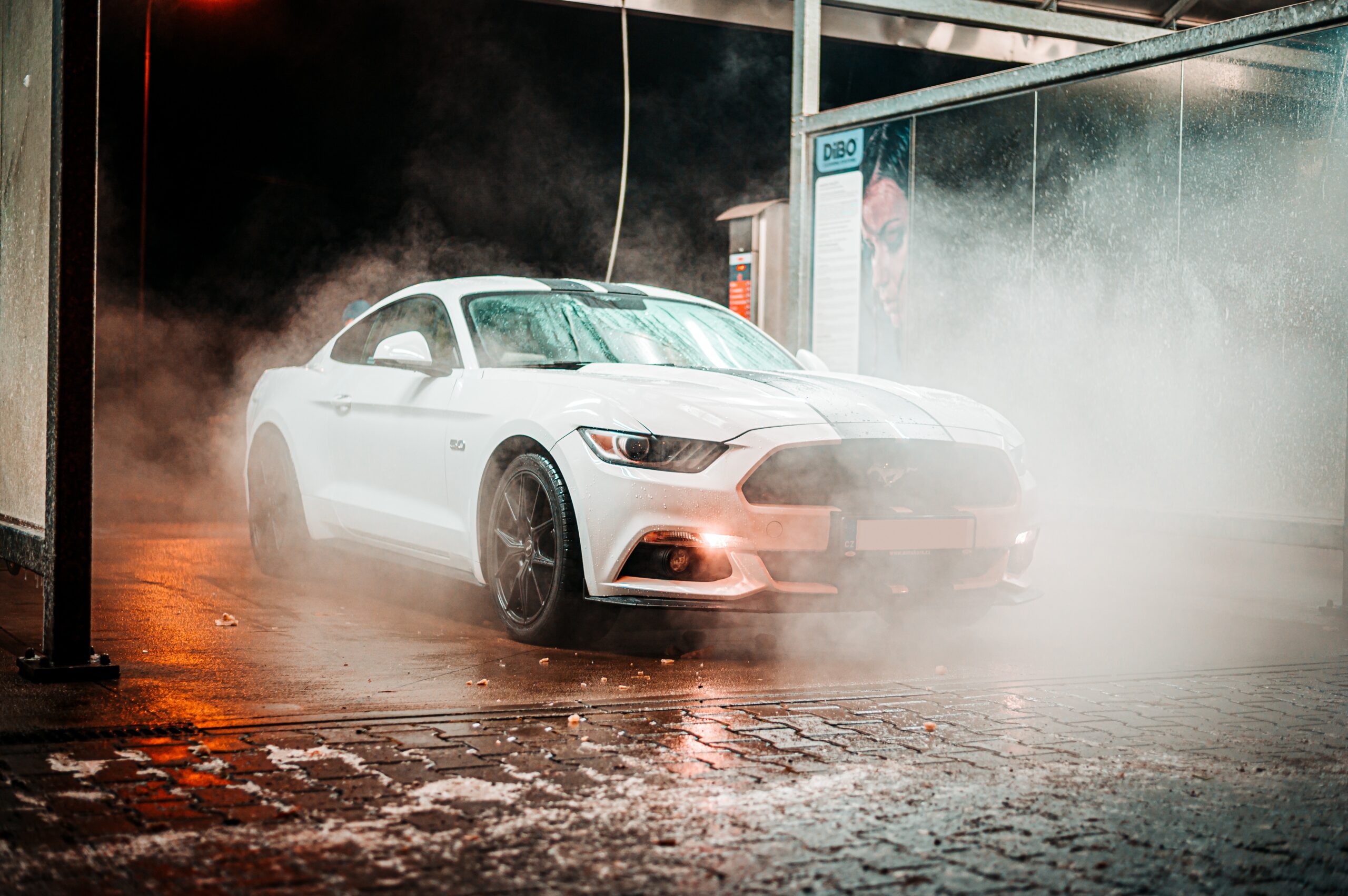 A 2014 Mustang gets cleaned in the night under the lights of the wash box