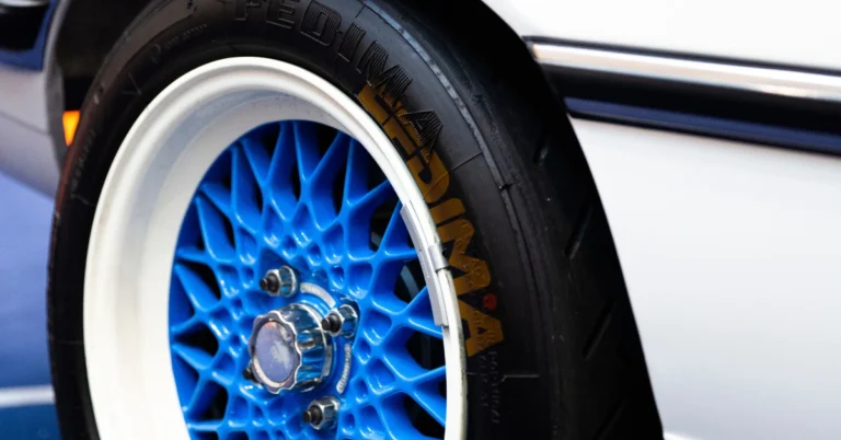 A Black car tire with white and brown letters on a blue rim
