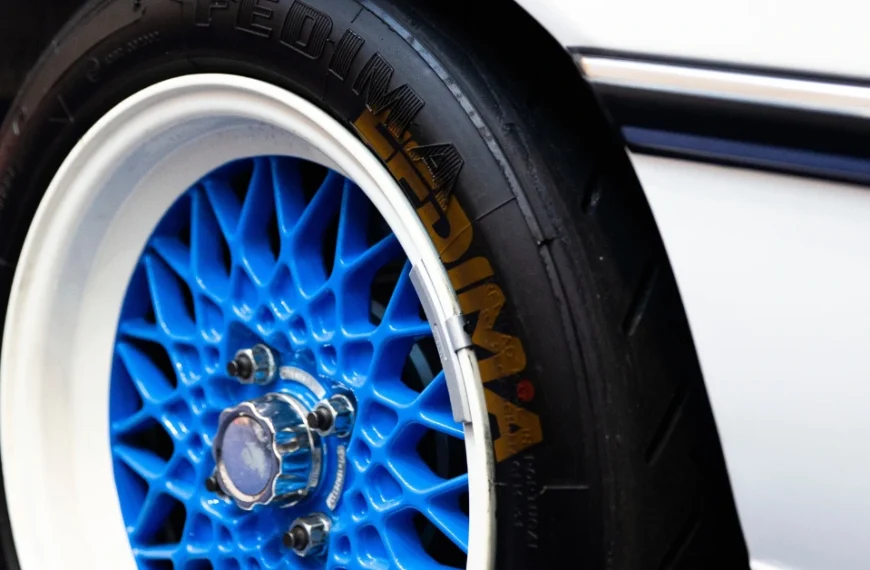 A Black car tire with white and brown letters on a blue rim