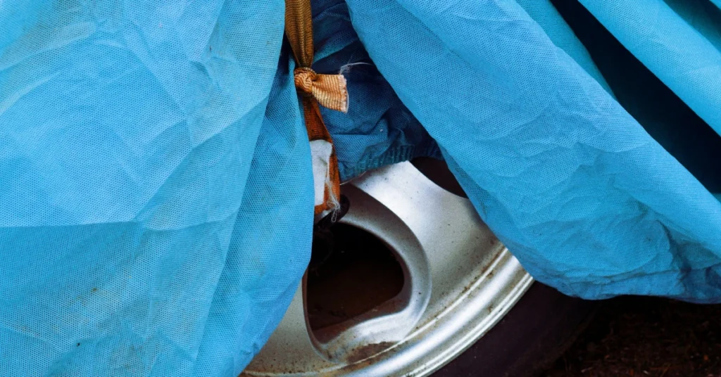 A small part of a silver rim looking out while wrapped in a car tire cover