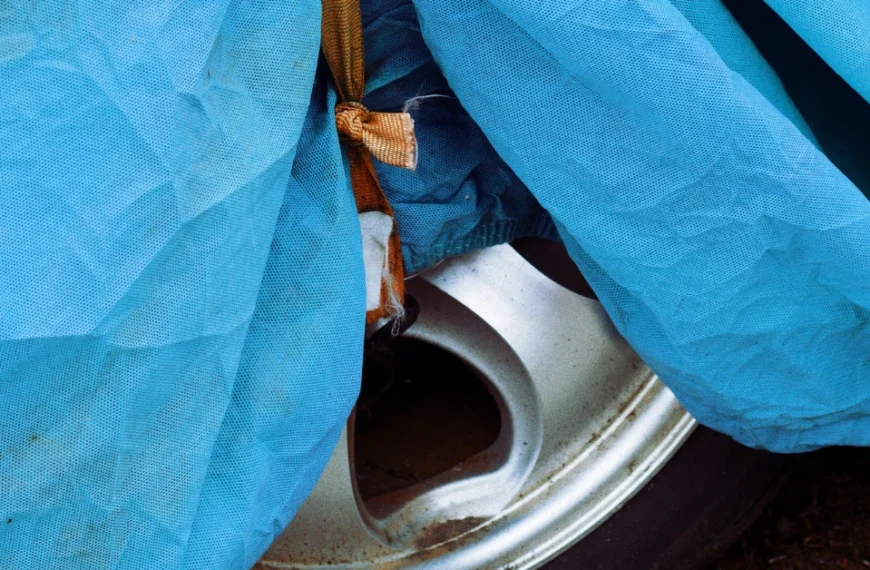 A small part of a silver rim looking out while wrapped in a car tire cover