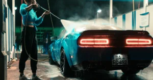 A woman is pressure washing her car at night