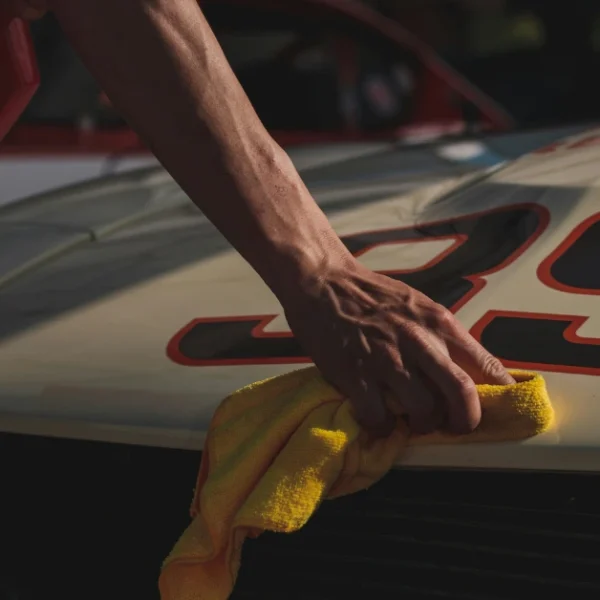 A Motorhood from a race car gets dried with a towel