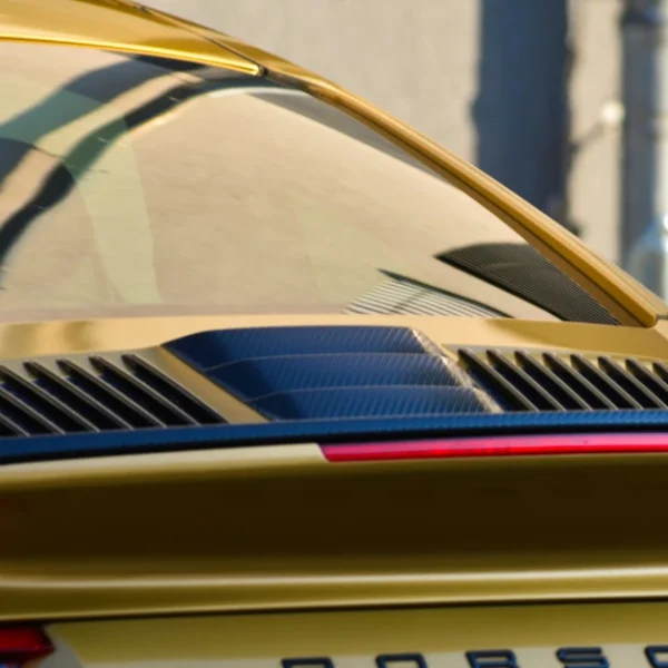 The tinted backwindow of a golden Porsche 911 Carrera