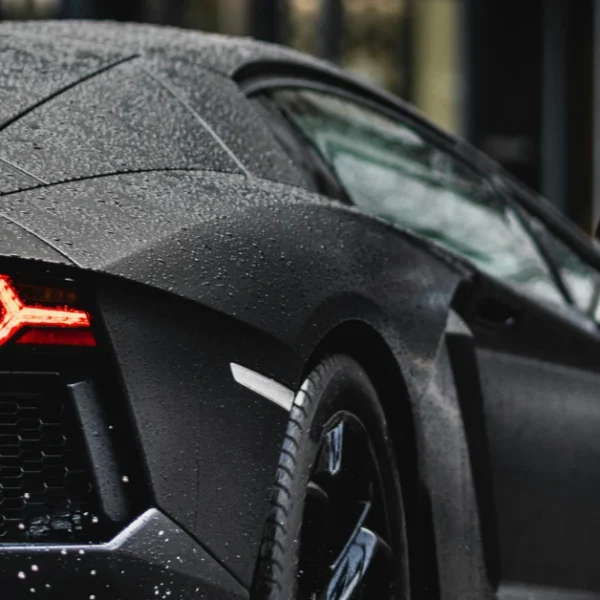 The back of a black Lamborghini driving on a street