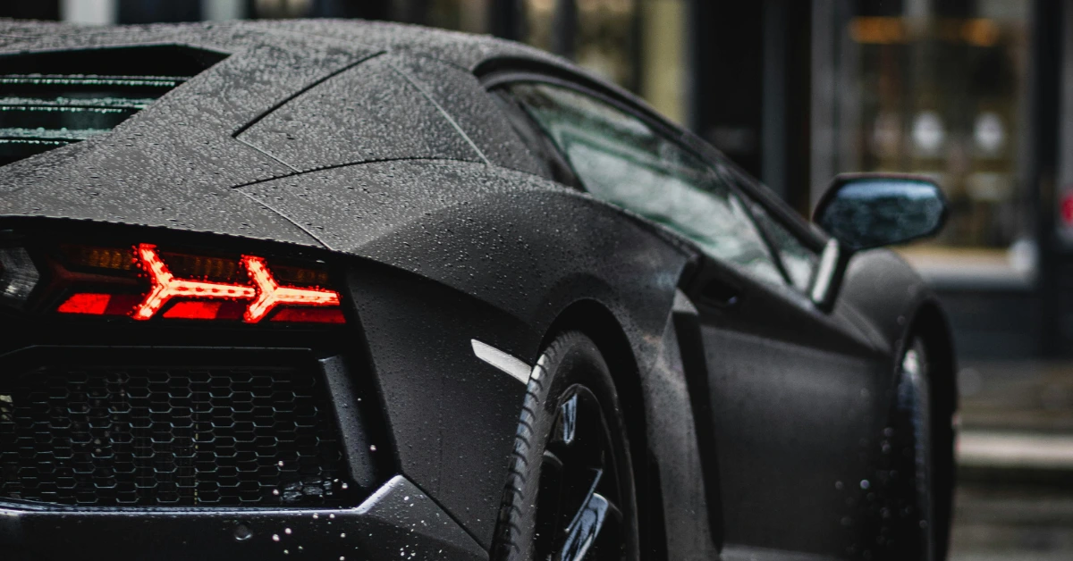 The back of a black Lamborghini driving on a street