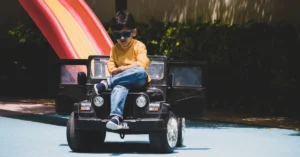 Boy with sunglasses on sitting on his Ride on Car