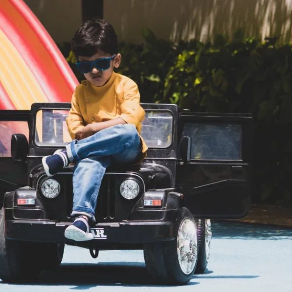Boy with sunglasses on sitting on his Ride on Car