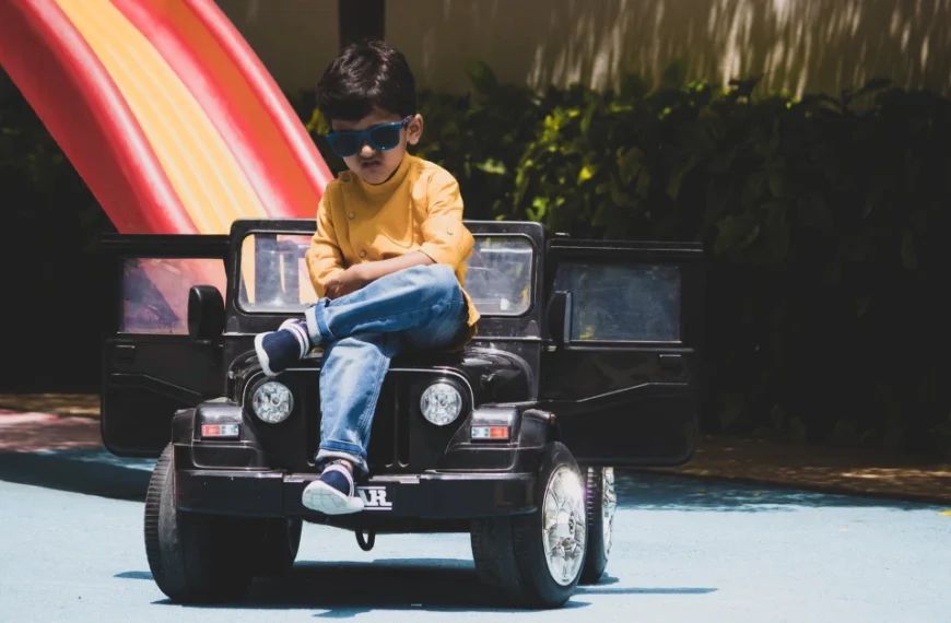 Boy with sunglasses on sitting on his Ride on Car