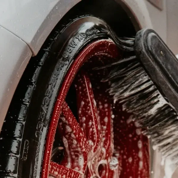 Red Car Rim get brushed with a Car wash Brush