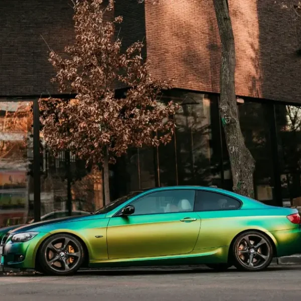 A Rainbowcolor wrapped BMW on the side of a street