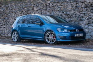 Blue Golf 7 standing in front of a stone wall