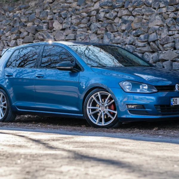 Blue Golf 7 standing in front of a stone wall