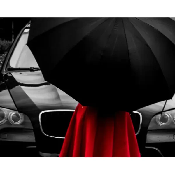 Woman with a red dress and a black umbrella in front of a all black bmw