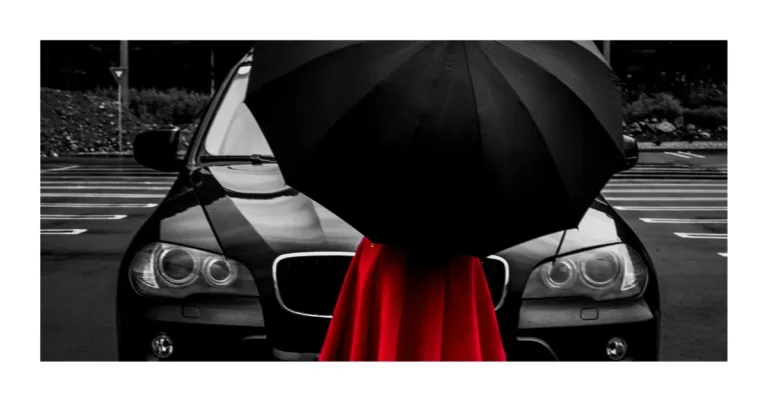 Woman with a red dress and a black umbrella in front of a all black bmw