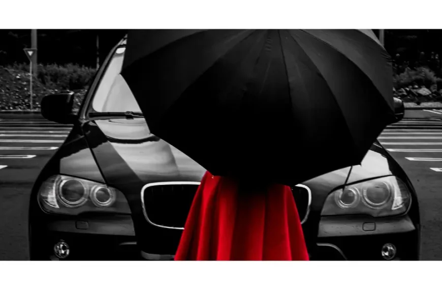 Woman with a red dress and a black umbrella in front of a all black bmw